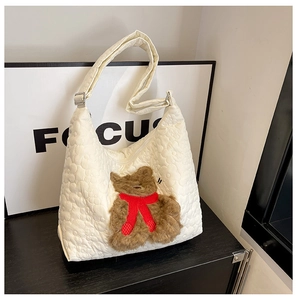 Detail of white quilted nylon tote bag featuring a cute 3D brown plush bear patch