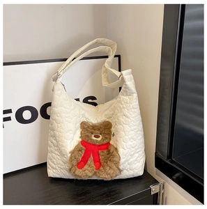 Close-up of white quilted nylon tote bag with a cute brown plush bear wearing a red scarf