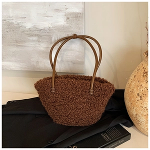Detailed close-up of brown plush teddy bucket bag with dark brown slim handles