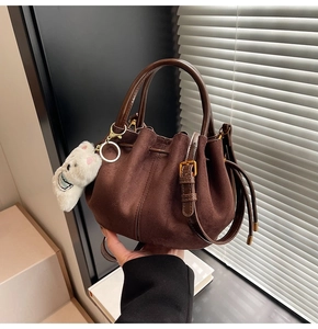 Détail du sac seau en daim marron foncé avec cordon de serrage et breloque ours en peluche
