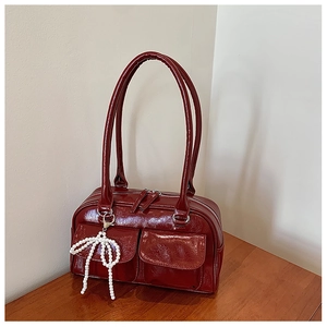 Détail du sac Boston bordeaux montrant le cuir verni craquelé et le pendentif perle