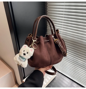 Détail du sac seau en daim marron avec cordon de serrage et breloque chien en peluche