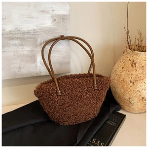 Detail of plush teddy brown tote bag with smooth cylindrical handles and spherical accents