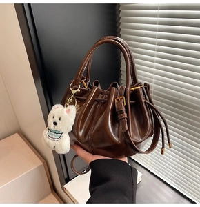 Détail du sac seau plissé marron foncé avec charm chien en peluche et bandoulière