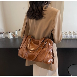 Détail d'un grand sac cabas vintage marron porté par un mannequin en intérieur chaleureux