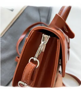 Gros plan des crochets et accessoires en métal argenté sur le sac à bandoulière marron