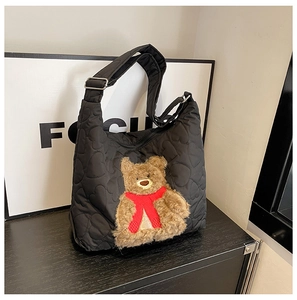Detail of black quilted heart-pattern bag featuring a cute plush bear with a red scarf