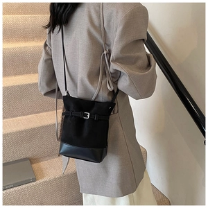 Detail of black bucket bag featuring suede and leather contrast with silver buckle