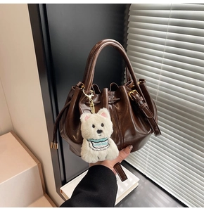 Détail du sac seau marron foncé brillant avec cordon de serrage et breloque ourson
