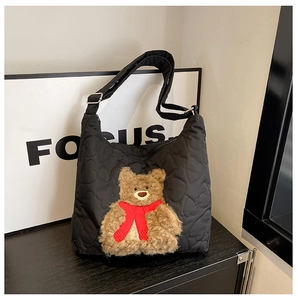 Detail of black nylon tote featuring heart quilting and a plush bear charm with red scarf