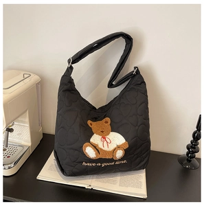 Detail shot of black quilted nylon tote bag with cute bear embroidery and embroidered slogan