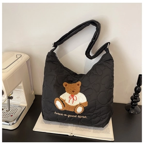 Detail of black quilted tote bag featuring heart patterns and teddy bear embroidery