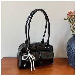Vue détaillée du sac Boston en cuir verni noir avec poches frontales et pendentif nœud en perles