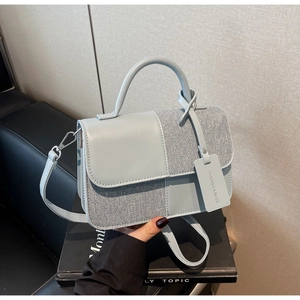 Détail de la texture patchwork en cuir et denim sur le petit sac à main bleu-gris