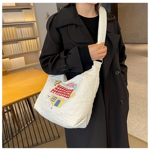 Detail view of white quilted crossbody bag with floral texture and cute cartoon embroidery