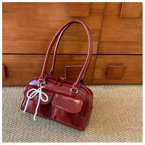 Sac Boston en cuir verni rouge foncé avec charmant pendentif nœud en perles sur tapis
