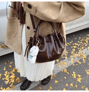 Détail du sac seau plissé marron foncé avec charm lapin en peluche et cordon de serrage