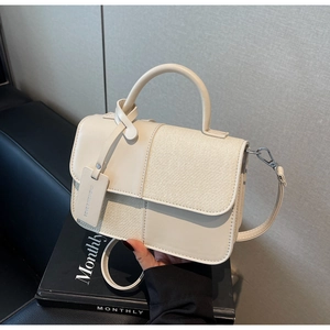 Détail d'un sac à main patchwork en tweed et cuir posé sur un livre noir élégant