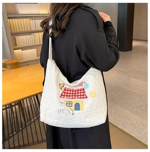 Detail of white quilted nylon tote bag with colorful embroidery and decorative buttons