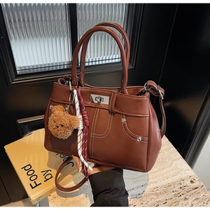 Detail of vintage brown PU leather handbag with silver twist lock and plush bear charm