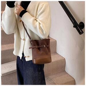 Détail du sac seau en daim marron caramel avec boucle en cuir et bandoulière réglable