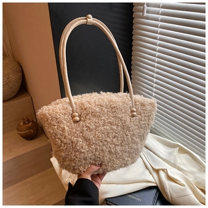 Detail of soft cream plush bucket bag made of curly fleece fabric held by hand