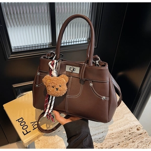 Detail of dark brown leather handbag featuring white stitching and silver twist lock closure