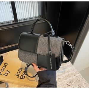 Détail de la texture mixte en cuir noir et tissu gris sur le sac à main de forme carrée