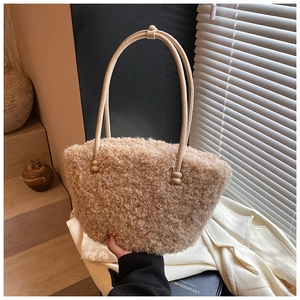 Close-up of beige sherpa tote bag with slim leather handles and decorative beads