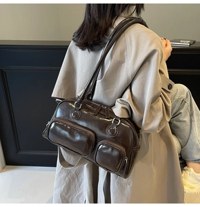 Close-up of a retro dark brown glossy shoulder bag featuring double front zipper pockets
