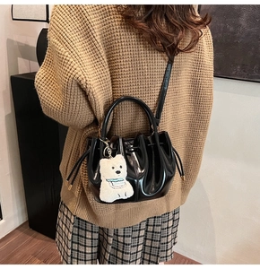 Détail du sac seau noir brillant avec cordon de serrage et breloque ours blanc en peluche