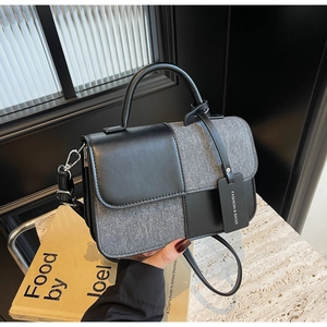 Détail d'un sac bandoulière bicolore en cuir noir et patchwork de denim gris chiné