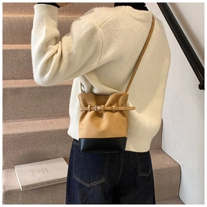 Détail du sac seau vintage en daim marron et cuir lisse noir avec boucle décorative