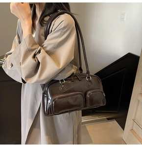 Detail of a dark brown glossy leather bowling shoulder bag with silver zippers and long handles