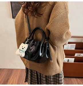 Détail du sac seau noir brillant avec cordon de serrage et breloque petit ours