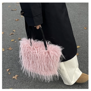 Gros plan d'un sac à main en fausse fourrure rose avec poignées en cuir noir en extérieur