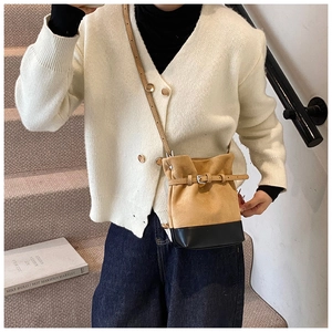 Detail of two-tone bucket bag with belt buckle accent and leather shoulder strap