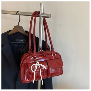 Détail du sac Boston en cuir verni bordeaux avec poches cargo et breloque nœud en perles