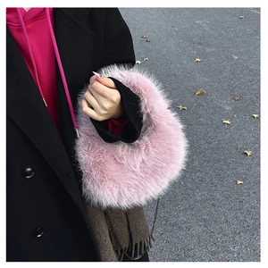 Dettaglio borsa a mano rosa in ecopelliccia con catena metallica su cappotto nero