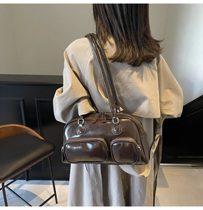 Detail of dark brown glossy leather bowling bag featuring front zip pockets on trench coat