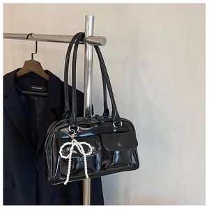 Détail du sac Boston noir brillant avec un grand charme de nœud en perles blanches