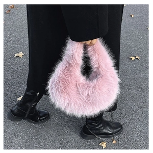 Borsa hobo rosa in pelliccia sintetica con catena indossata su un cappotto nero