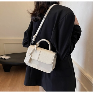 Détail d'un sac à bandoulière en cuir crème porté par un mannequin féminin