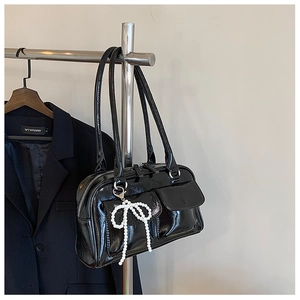 Détail du sac Boston noir brillant avec breloque nœud perlé et doubles lanières