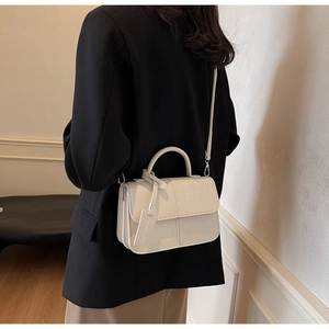 Petit sac bandoulière crème en patchwork porté avec un blazer sombre élégant