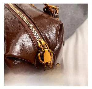 Close-up of premium gold-tone metal zipper and textured brown leather on retro bag