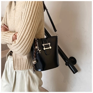 Pendentifs étoile et cloche argentés sur un sac seau vintage en cuir noir chic