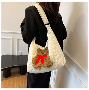 Detail view of large white quilted nylon tote bag with cute brown bear charm on shoulder