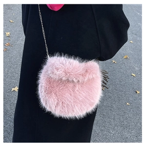 Dettaglio della borsa a tracolla in peluche rosa con catena in metallo su cappotto