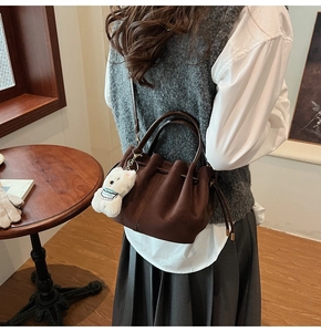 Détail du sac seau marron foncé en suédine avec cordon de serrage et breloque ourson